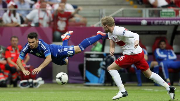 Ein griechischer und ein polnischer Fußballspieler kämpfen um den Ball.