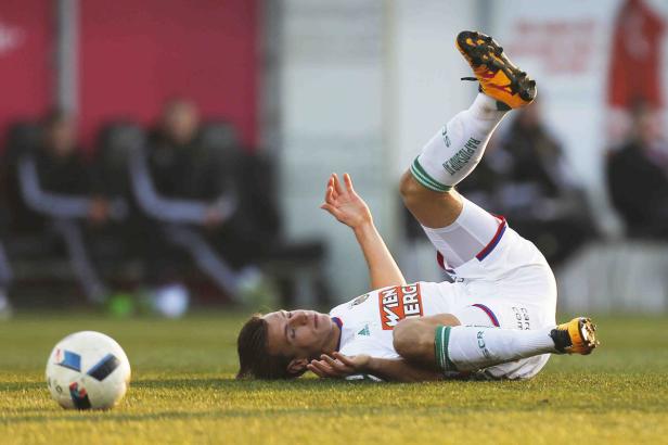 Ein Fußballspieler liegt nach einem Zweikampf auf dem Rasen.