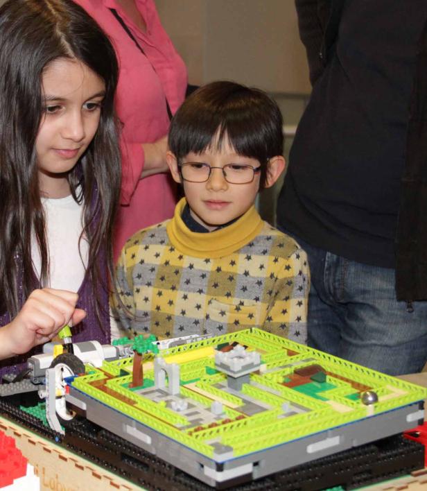Zwei Kinder spielen mit einem Labyrinth aus Legosteinen.