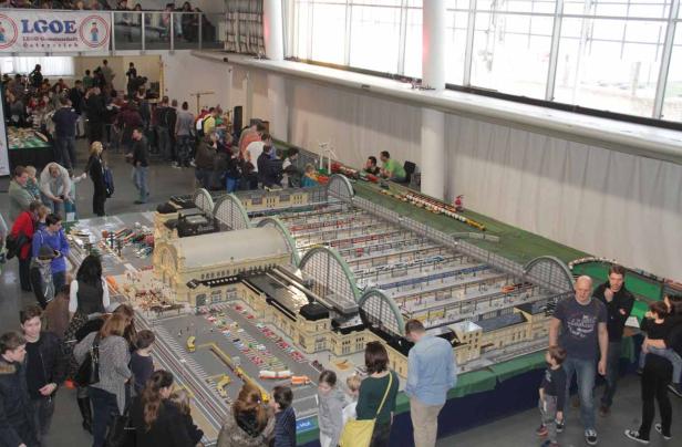 Besucher betrachten ein großes Modell eines Bahnhofs aus Legosteinen.