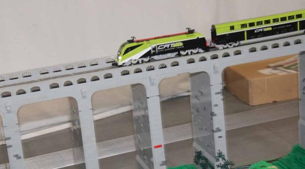 Ein Spielzeugeisenbahnzug der Marke CAT fährt über eine Brücke.