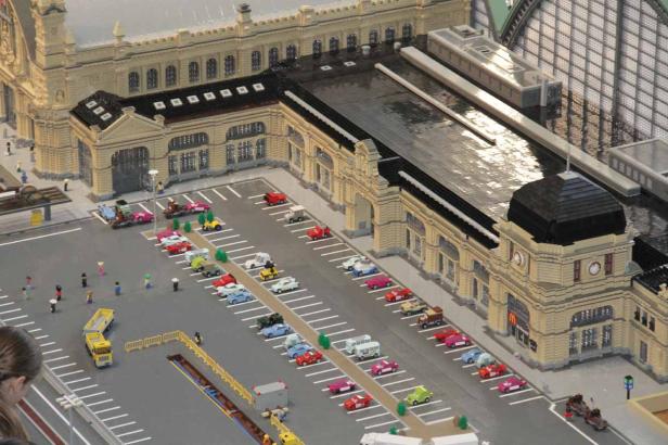 Ein Lego-Modell eines Bahnhofs mit Parkplatz und vielen kleinen Autos.
