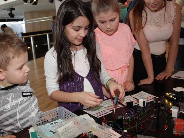 Eine Gruppe Kinder arbeitet an einem Elektronikprojekt mit Drähten und Bauteilen.