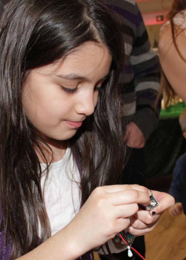 Ein junges Mädchen mit langen, dunklen Haaren bastelt an einem elektronischen Gerät.