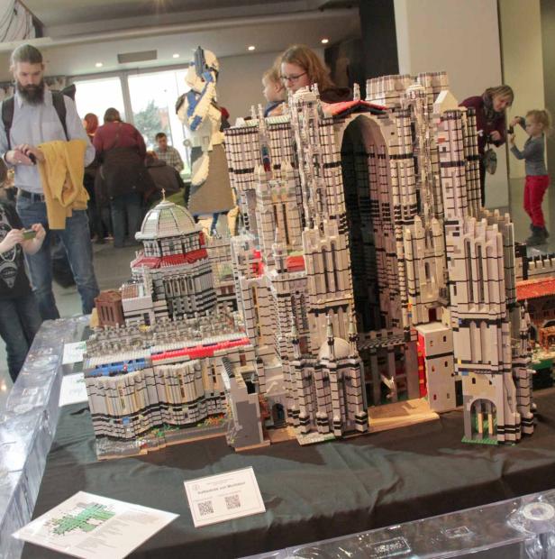 Eine detaillierte Lego-Nachbildung einer Kathedrale wird von Menschen betrachtet.