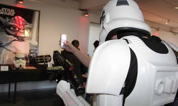 Ein Stormtrooper macht ein Foto von einem „Star Wars“-Ausstellungsstück.