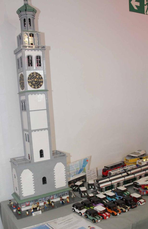 Ein Lego-Modell des Augsburger Perlachturms mit kleinen Autos und Bussen davor.