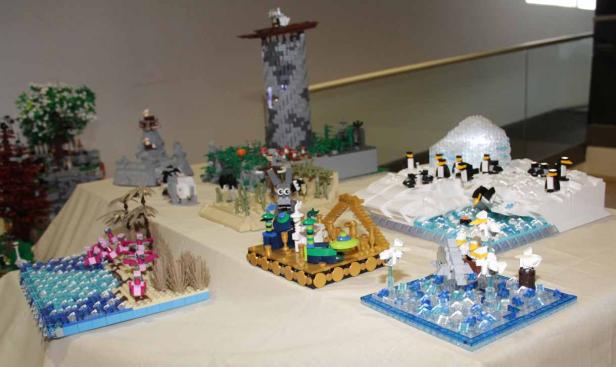 Mehrere Lego-Dioramen zeigen verschiedene Szenen, darunter Pinguine, eine Burg und eine tropische Insel.