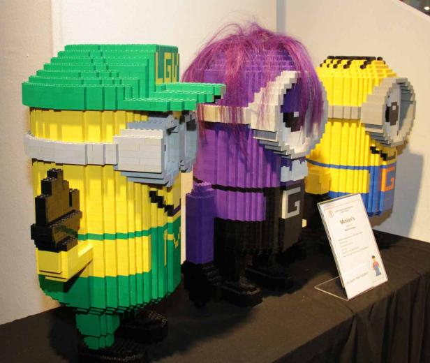Drei Minions-Figuren aus Legosteinen, darunter ein lilafarbener mit lila Haaren.
