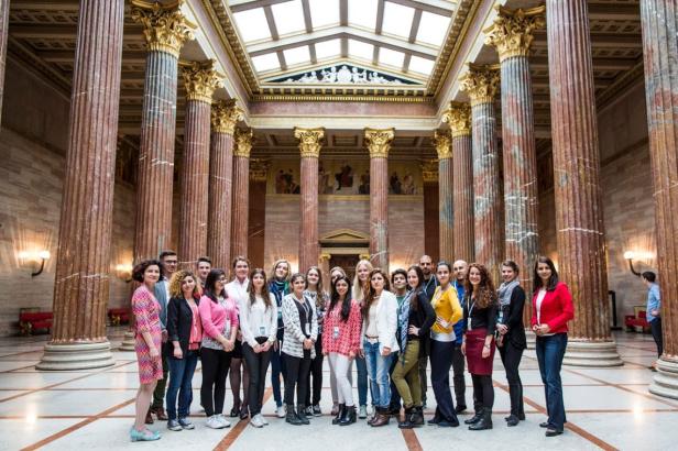 Eine Gruppe von Menschen steht in einer Halle mit hohen Säulen.