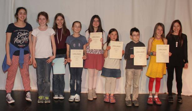 Eine Gruppe von Kindern steht mit Urkunden auf einer Bühne.