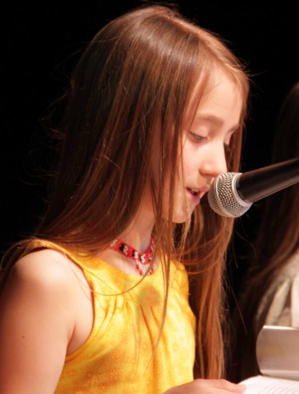 Ein junges Mädchen spricht in ein Mikrofon.