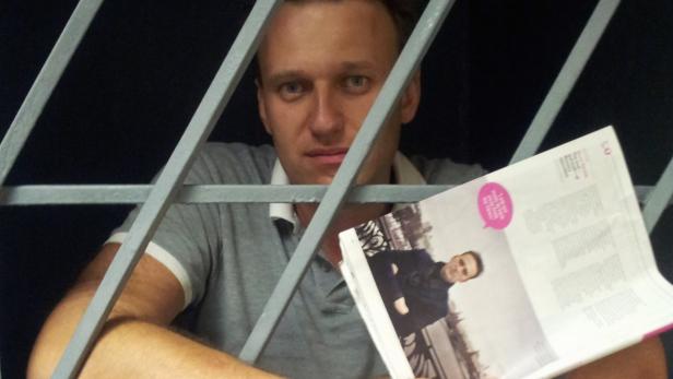 Blogger und Anwalt Alexej Nawalny saß schon öfter hinter Gittern - jetzt wird wieder gegen ihn ermittelt. Alexei Nawalny hinter Gittern mit einer Zeitschrift in der Hand.