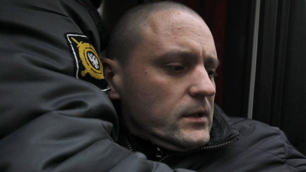 Der Linksradikale Sergej Udalzow ist den Behörden ein Dorn im Auge. Ein Mann wird von einem Beamten mit einem Abzeichen an der Jacke abgeführt.