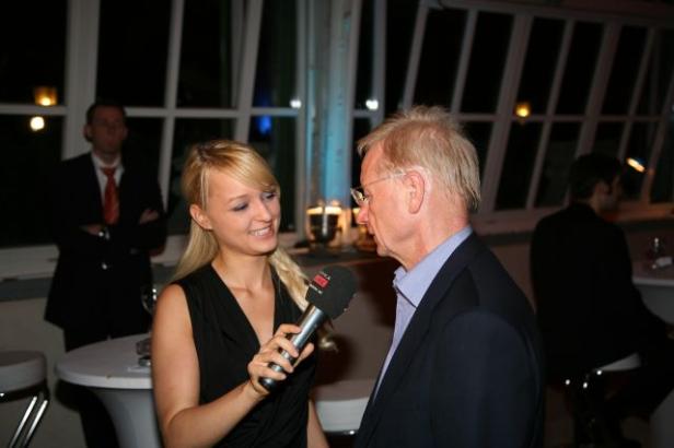 Eine junge Frau interviewt einen älteren Mann mit einem Mikrofon.