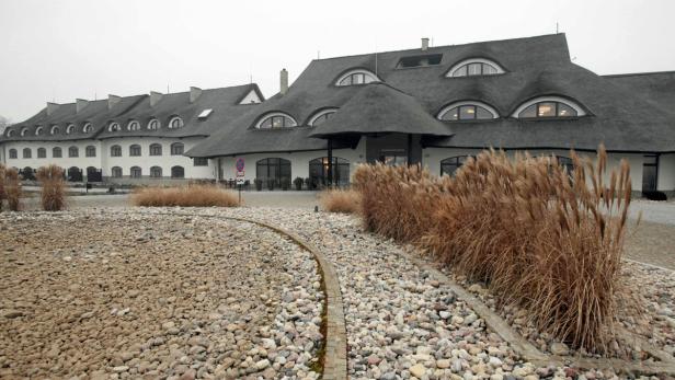 Ein großes Gebäude mit Reetdach und einem Kiesweg im Vordergrund.