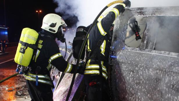 Zwei Feuerwehrleute löschen einen Brand in der Nacht.
