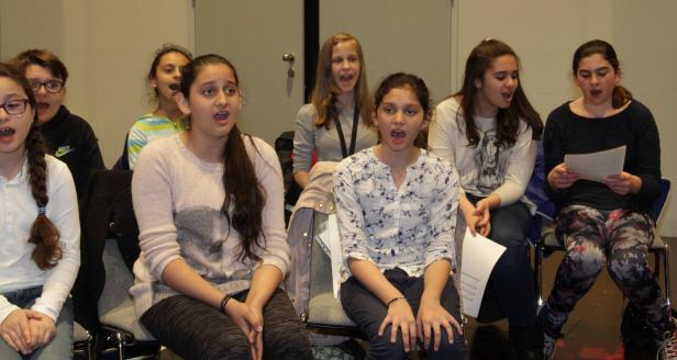 Eine Gruppe Jugendlicher sitzt und singt gemeinsam.