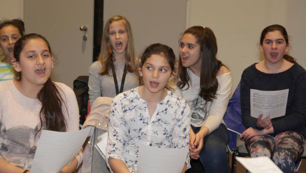 Eine Gruppe junger Mädchen singt gemeinsam aus Notenblättern.
