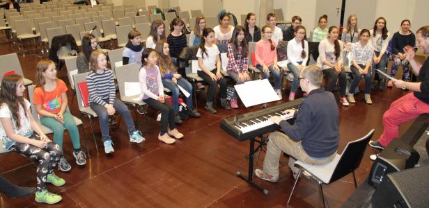 Ein Musiklehrer spielt Klavier vor einer Gruppe von Teenagern.