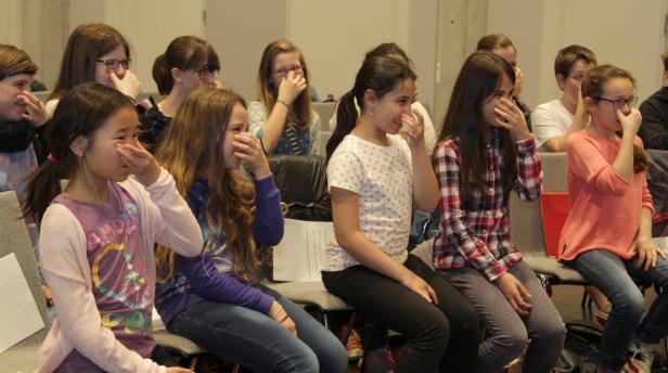 Eine Gruppe junger Mädchen sitzt in einem Raum und hält sich die Nase zu.