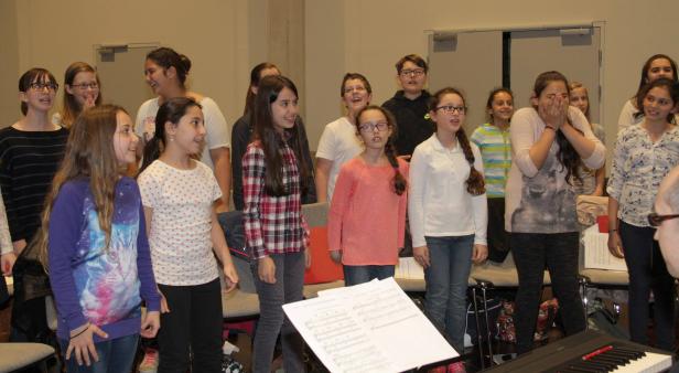 Eine Gruppe von Kindern steht vor Notenständern und singt.