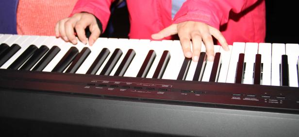 Eine Person spielt auf einem schwarzen Keyboard mit weißen und schwarzen Tasten.