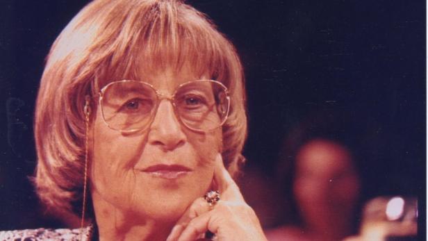 Schrieb "Die friedfertige Frau" Eine ältere Frau mit Brille und Ring blickt in die Ferne.
