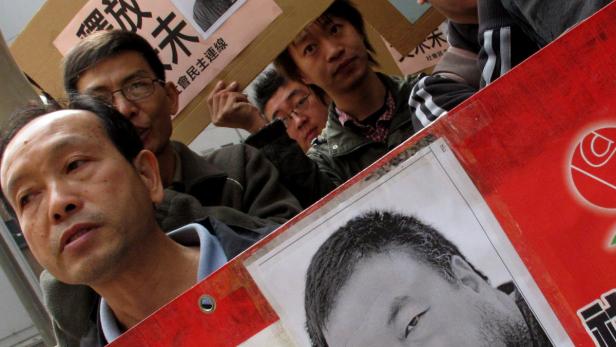 Ai Weiwei wurden nach regierungskritischen Äußerungen 2011 in Haft gesteckt. Landsleute und Supporter protestierten. Mehrere asiatische Männer demonstrieren mit Schildern und Porträts.
