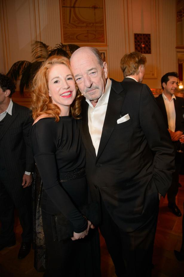 Eine rothaarige Frau umarmt einen älteren Mann im Anzug.