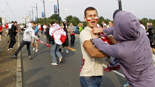 Ein Mann mit polnischen Flaggen auf den Wangen wird auf einer Straße angegriffen.
