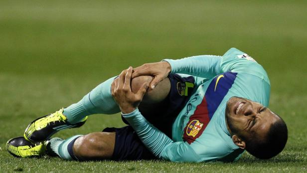 Ein Fußballspieler liegt mit schmerzverzerrtem Gesicht auf dem Rasen und hält sein Knie fest.