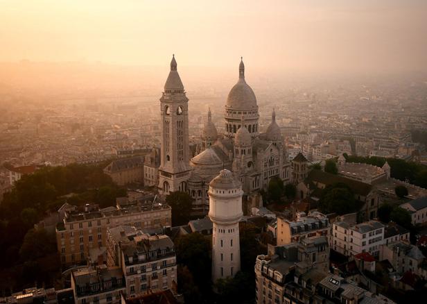 Die Basilika Sacré-Cœur de Montmartre überragt die Stadt Paris im goldenen Morgenlicht.