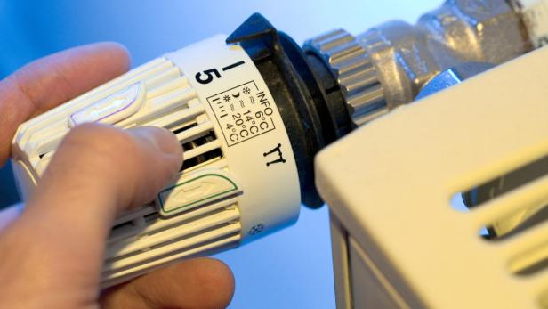 Eine Hand stellt einen Heizkörperthermostat auf Stufe 5.