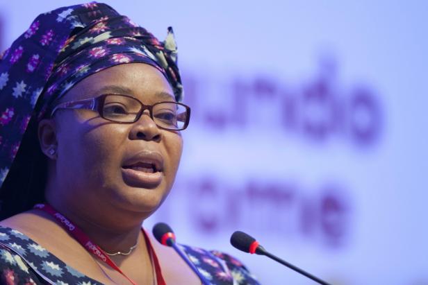 Friedensnobelpreisträgerin Leymah Gbowee Eine Frau mit Brille und Kopfbedeckung spricht vor Mikrofonen.