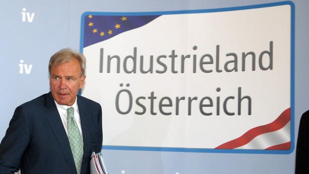 Ein Mann in einem Anzug steht vor einem Schild mit der Aufschrift „Industrieland Österreich“.