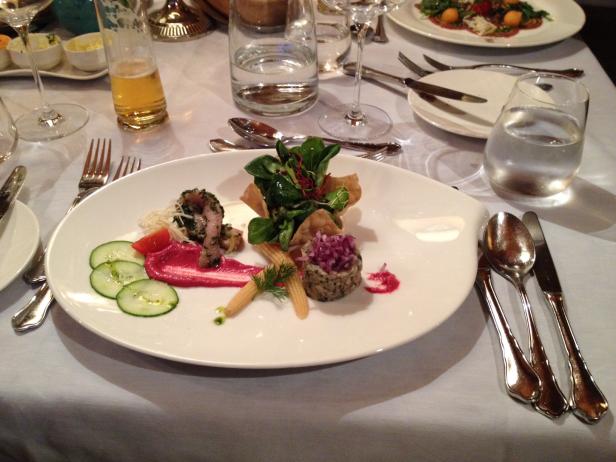 Ein Teller mit einer kunstvollen Vorspeise auf einem gedeckten Tisch.