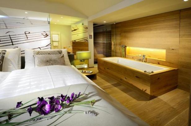 Ein Hotelzimmer mit einem Bett mit Blumen und einem Holzbadezimmer im Hintergrund.