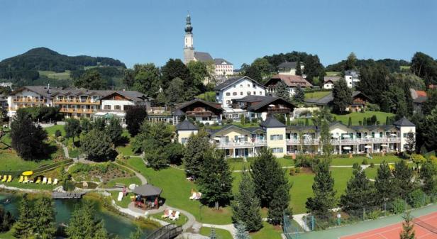Ein Blick auf ein Resort mit Häusern, einem See und einer Kirche im Hintergrund.