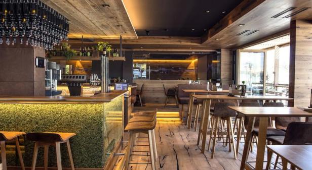 Innenansicht eines Restaurants mit Bar und Holzeinrichtung.