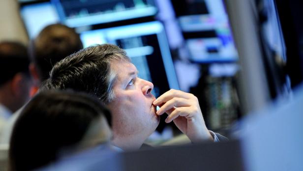 Ein Mann blickt auf einen Bildschirm mit Börsendaten und scheint nachzudenken.