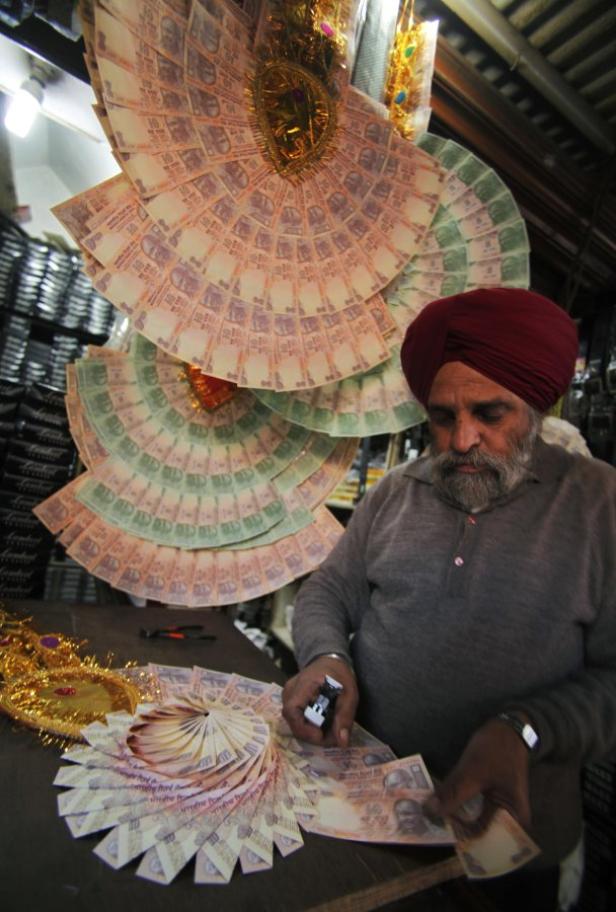 Ein Mann mit Turban arrangiert Geldscheine zu dekorativen Fächern.