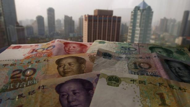 Verschiedene chinesische Yuan-Banknoten vor einer Skyline.