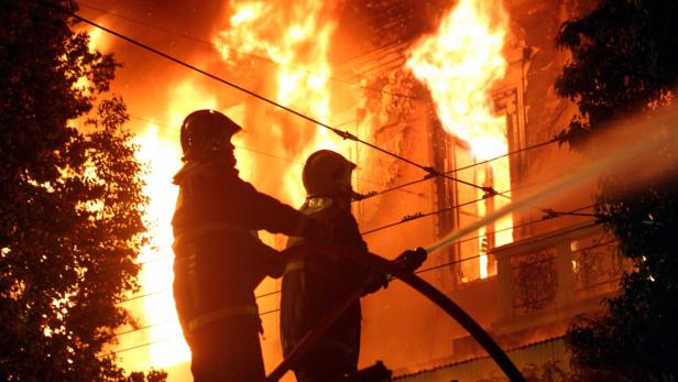 Zwei Feuerwehrleute bekämpfen einen Brand in einem Gebäude.