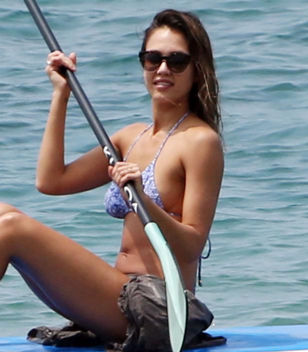 Jessica Alba paddelt auf einem Surfbrett im Meer.