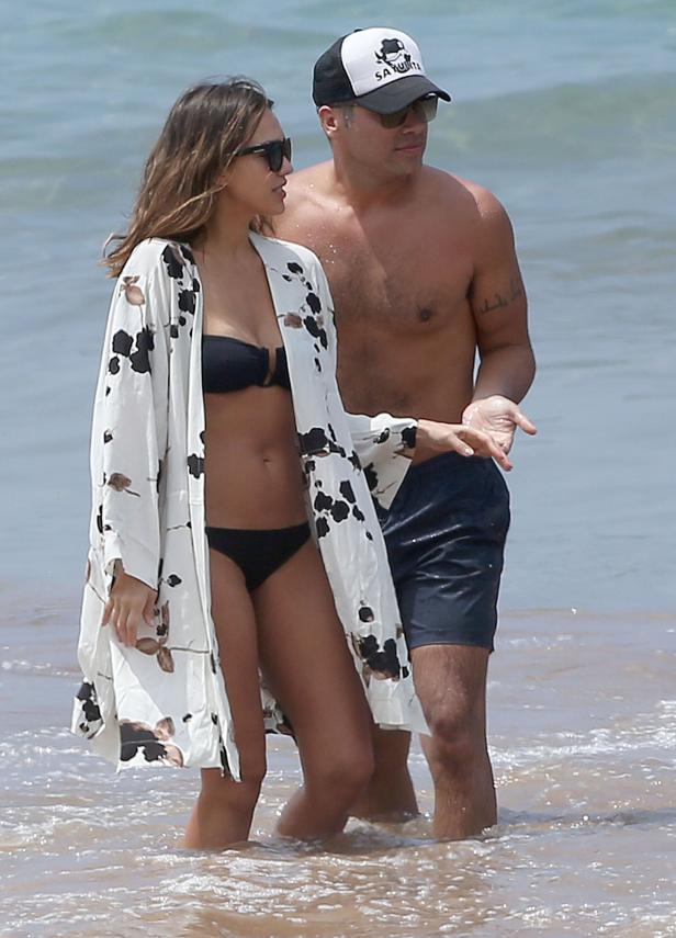 Jessica Alba und ein Mann stehen im seichten Wasser am Strand.