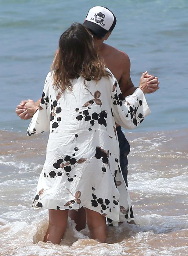 Ein Paar steht Hand in Hand im seichten Wasser am Strand.