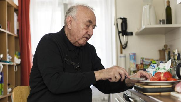 Ein älterer Mann schneidet Tomaten in einer Küche.