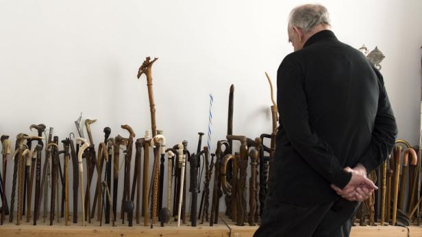 Ein Mann betrachtet eine Sammlung von Spazierstöcken.