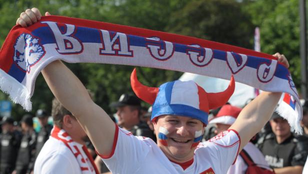 Ein Mann mit Gesichtsbemalung und einem rot-weiß-blauen Wikingerhut hält einen passenden Schal hoch.